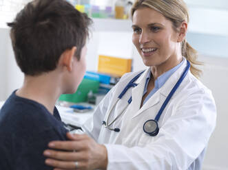 Ärztin gibt einem Jungen während eines Termins in der Klinik Anweisungen - ABRF00620