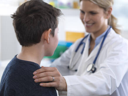 Ärztin gibt einem Jungen während eines Termins in der Klinik Anweisungen - ABRF00622