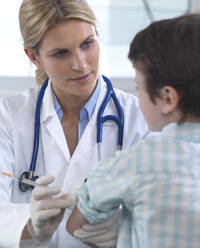 Female doctor giving a young boy a vaccination in the clinic - ABRF00625