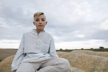 Portrait of blond boy, sitting on a hay bale - KMKF01076