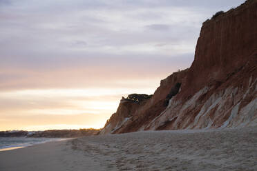 Felsiger Sandstein an der Atlantikküste gegen bewölkten Himmel bei Sonnenuntergang, Algarve, Portugal - WIF04009