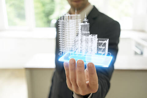 Geschäftsmann hält Hologramm eines Architekturmodells, lizenzfreies Stockfoto