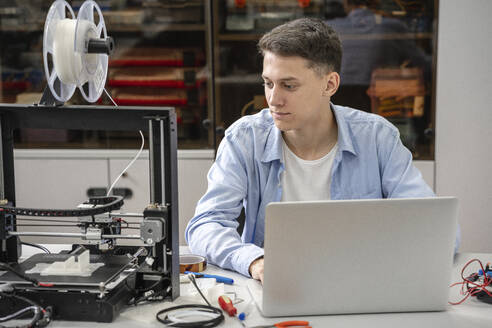 Student beim Einrichten eines 3D-Druckers mit Laptop - VPIF01455