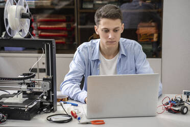 Student beim Einrichten eines 3D-Druckers mit Laptop - VPIF01456