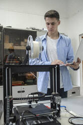 Student beim Einrichten eines 3D-Druckers mit Laptop - VPIF01470