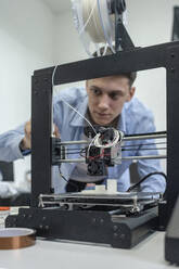 Student beim Einrichten eines 3D-Druckers mit Laptop - VPIF01473