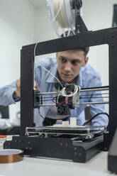 Student setting up 3D printer, using laptop - VPIF01473