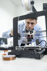 Student beim Einrichten eines 3D-Druckers mit Laptop - VPIF01474