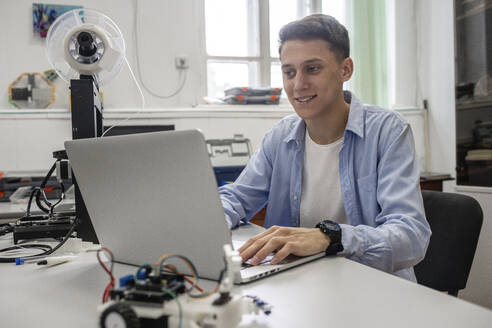 Student beim Einrichten eines 3D-Druckers mit Laptop - VPIF01478