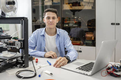 Student beim Einrichten eines 3D-Druckers mit Laptop - VPIF01479