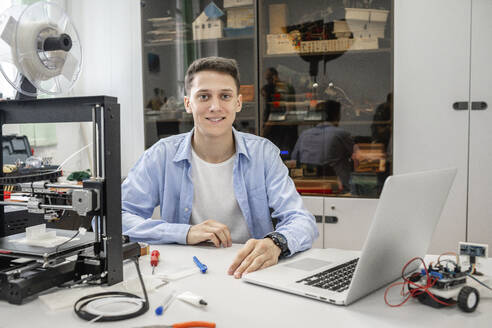 Student beim Einrichten eines 3D-Druckers mit Laptop - VPIF01481