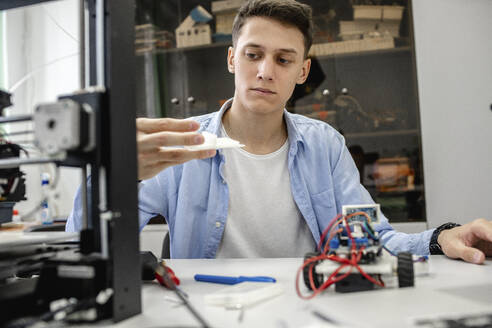 Student beim Einrichten eines 3D-Druckers mit Laptop - VPIF01484