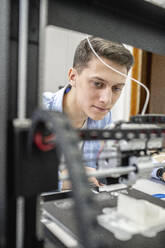 Student setting up 3D printer, close up - VPIF01496