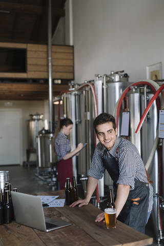 Lächelnder Jungunternehmer bei der Arbeit in einer Brauerei, lizenzfreies Stockfoto