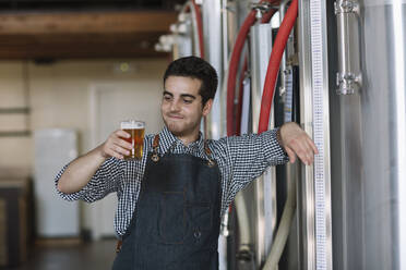 Porträt eines selbstbewussten jungen Mannes mit einem Bierglas in einer Brauerei - ALBF01075