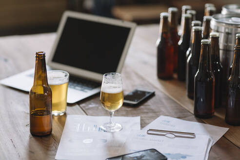 Beer bottles, glasses, documents and laptop on table - ALBF01082