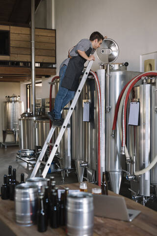 Junger Unternehmer bei der Arbeit am Tank in einer Brauerei, lizenzfreies Stockfoto