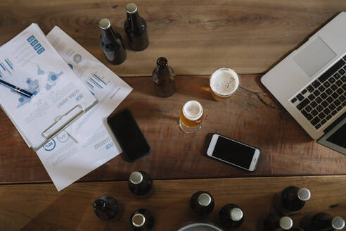 Beer bottles, glasses, documents, smartphones and laptop on table - ALBF01091