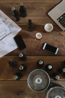 Beer bottles, glasses, documents, smartphones and laptop on table - ALBF01092