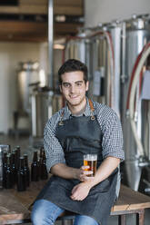Porträt eines lächelnden jungen Mannes, der in einer Brauerei ein Bier trinkt - ALBF01096