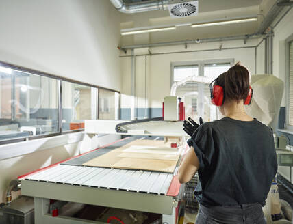 Rear view of woman at CNC machine in workshop - CVF01467