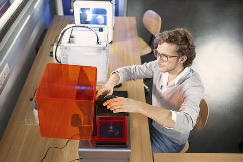 Techniker sitzt am Tisch mit 3D-Drucker, lizenzfreies Stockfoto