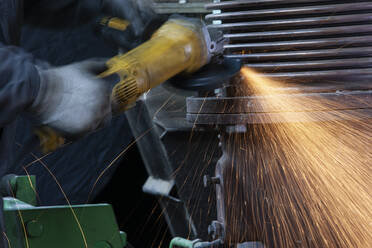 Nahaufnahme eines Arbeiters mit einem Winkelschleifer in einer Fabrik - CVF01493