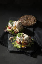 High angle view of open faced sandwich served on table against black background - MAEF12928