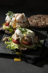 Close-up of open faced sandwich on table against black background - MAEF12930
