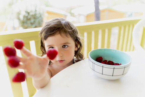 Niedliches kleines Mädchen mit Himbeeren an den Fingerspitzen - GEMF03125