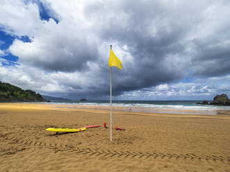 Gelbe Flagge am Strand von Laga vor bewölktem Himmel, spanisches Baskenland, Spanien - LAF02366