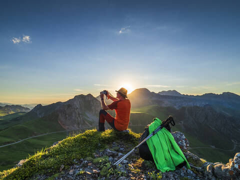 Seitenansicht eines älteren Mannes, der auf einem Bergpass sitzend fotografiert, Asturien, Spanien, lizenzfreies Stockfoto