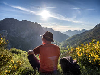 Rear view of senior man sitting on mountain against sky, Alto de La Farrapona, Asturias, Spain - LAF02373