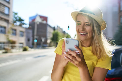 Glückliche junge Frau mit Smartphone in der Stadt, lizenzfreies Stockfoto