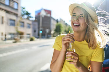 Happy young woman enjoying a drink in the city - BSZF01363