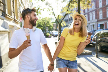 Happy young couple enjoying ice cream in the city - BSZF01371