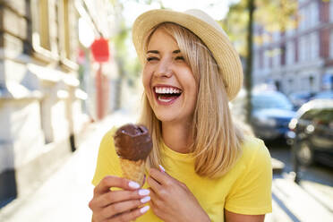 Carefree young woman enjoying an ice cream in the city - BSZF01373