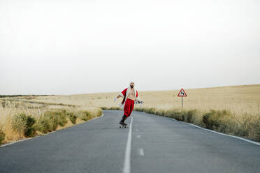 Santa Claus riding on longboard on country road - JCMF00178