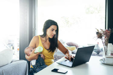 Mutter mit ihrem kleinen Jungen, der zu Hause einen Laptop benutzt - OCMF00618