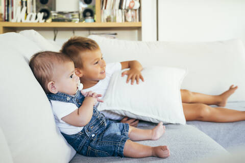 Zwei Jungen sitzen auf dem Sofa und sehen zu Hause fern, lizenzfreies Stockfoto