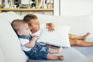 Two boys sitting on sofa and watching television at home - OCMF00619