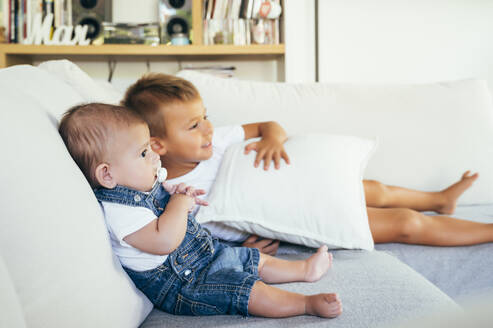 Zwei Jungen sitzen auf dem Sofa und sehen zu Hause fern - OCMF00619