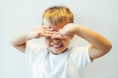 Boy covering his eyes in front of white background - OCMF00634