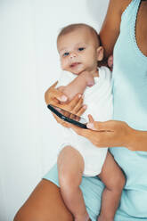 Mutter benutzt Smartphone und hält ihr Baby - OCMF00639