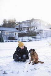 Boy sitting in snow with dog - JOHF00073