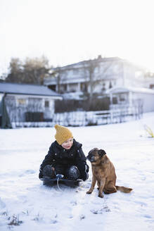 Junge sitzt mit Hund im Schnee - JOHF00073