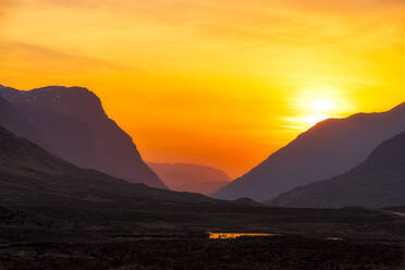 Blick auf die Berge vor dem orangefarbenen Himmel in Glencoe, Highlands, Schottland, UK - SMAF01454