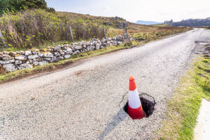 Verkehrskegel in einem Schlagloch auf der Straße auf der Isle of Skye, Highlands, Schottland, UK - SMAF01481