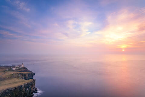 Neist Point Leuchtturm am Meer gegen bewölkten Himmel bei Sonnenuntergang in Waterstein, Isle of Skye, Highlands, Schottland, UK, lizenzfreies Stockfoto