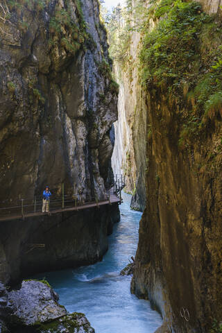 Ältere Frau auf Steg im Urlaub am Wasserfallsteig in der Leutaschklamm, Tirol, Österreich, lizenzfreies Stockfoto